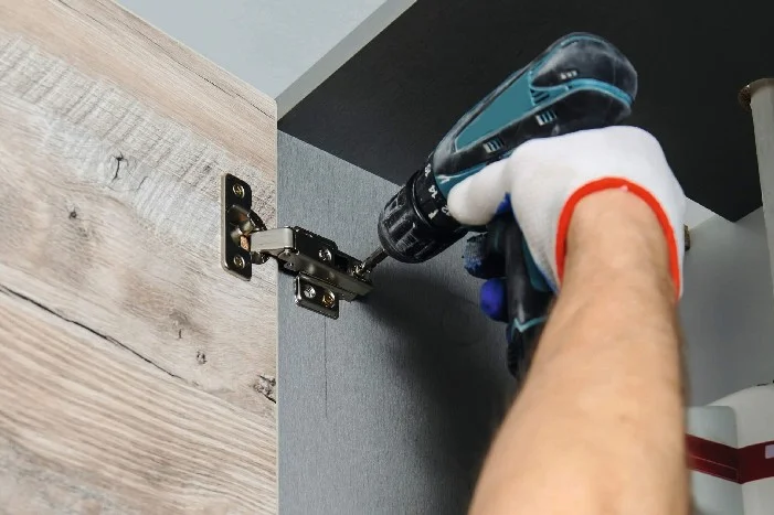 Person montiert Schranktür mit Akkuschreiber.